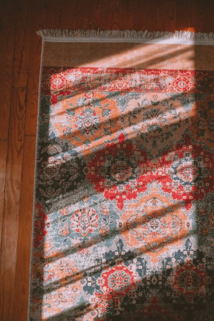 pexels-photo-7820362-7820362 Vibrant oriental rug with intricate patterns, sunlight creating dramatic shadows.